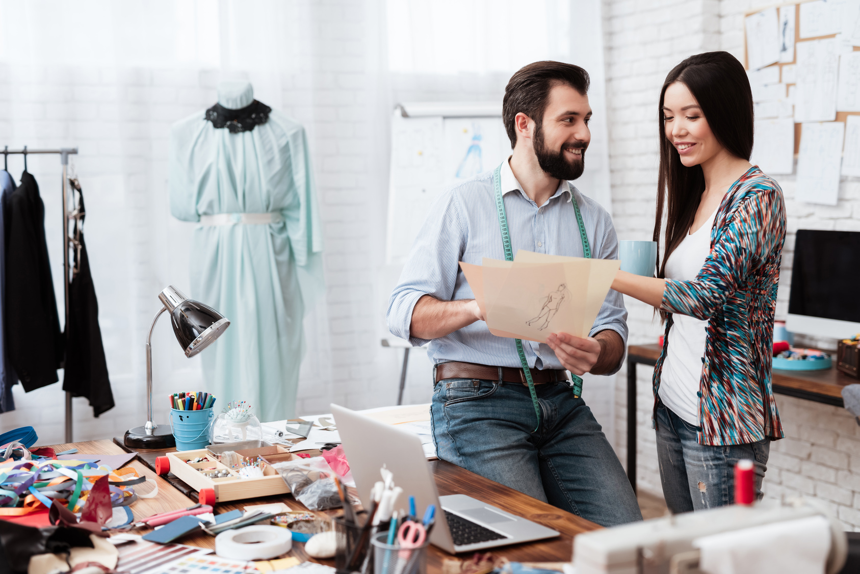 Two male and female fashion designers looking at drawing talking.